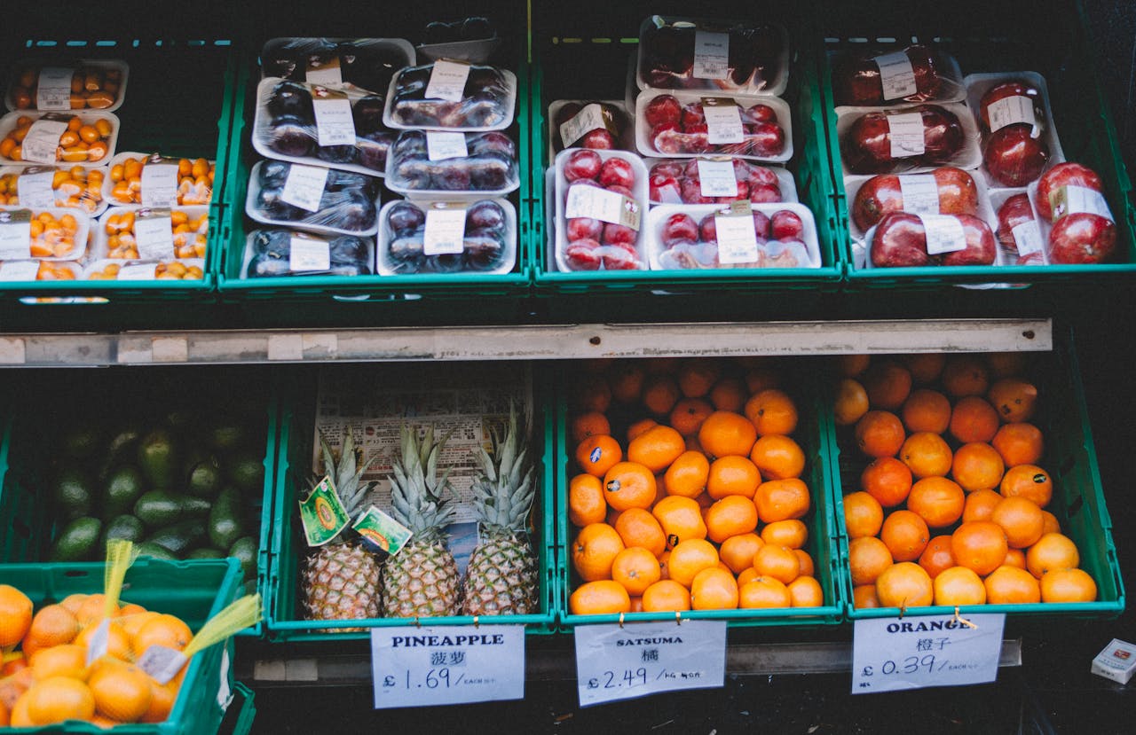 Services-03 Colorful assortment of fresh fruits displayed in a local market stall with price tags.