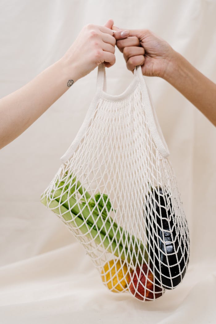 why-choose-us Hands holding a mesh bag filled with fresh vegetables, promoting sustainable shopping practices.